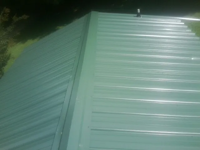 New green metal panels meeting at the ridge of a roof — Flat Roof Repair work by our crew in Sumpter