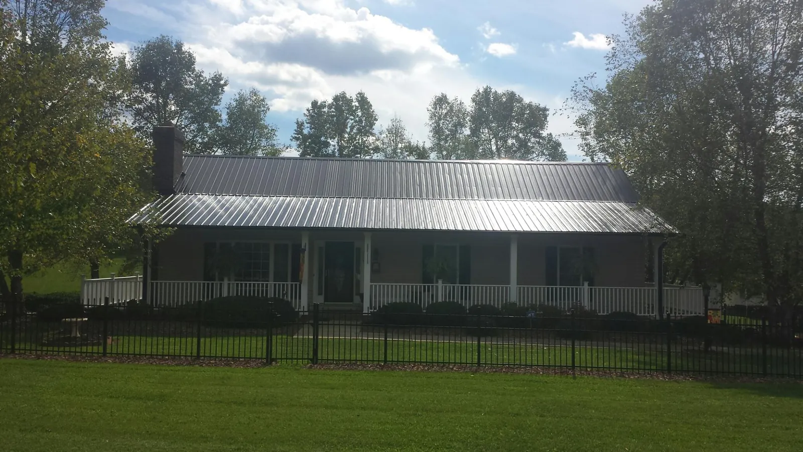 Gray metal roof on a brick ranch with a full width front porch — Gutter Guard Installation work by our crew in Sumpter