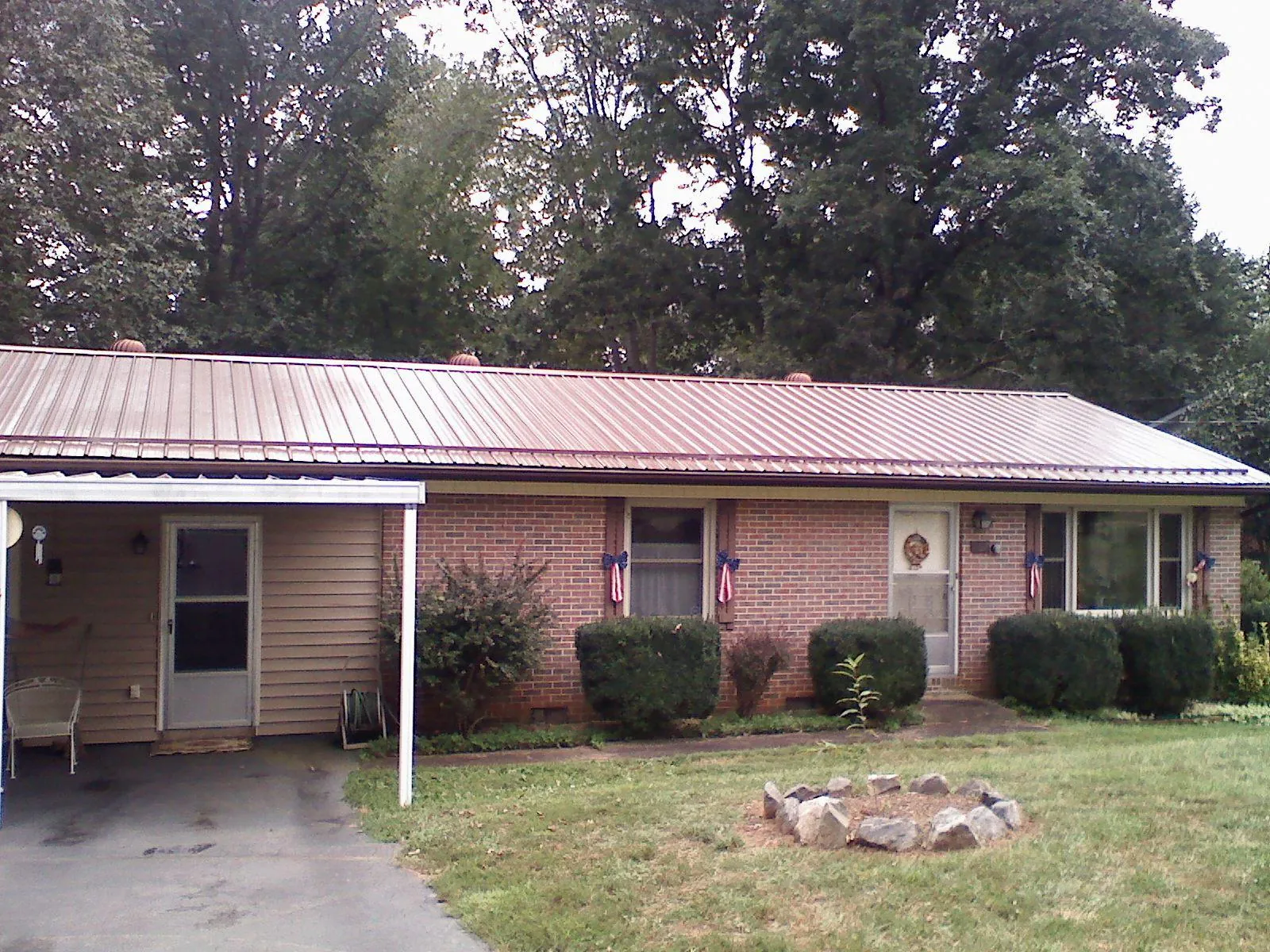 Bronze metal roof and carport on a brick ranch home — Roof Repair work by our crew in Sumpter