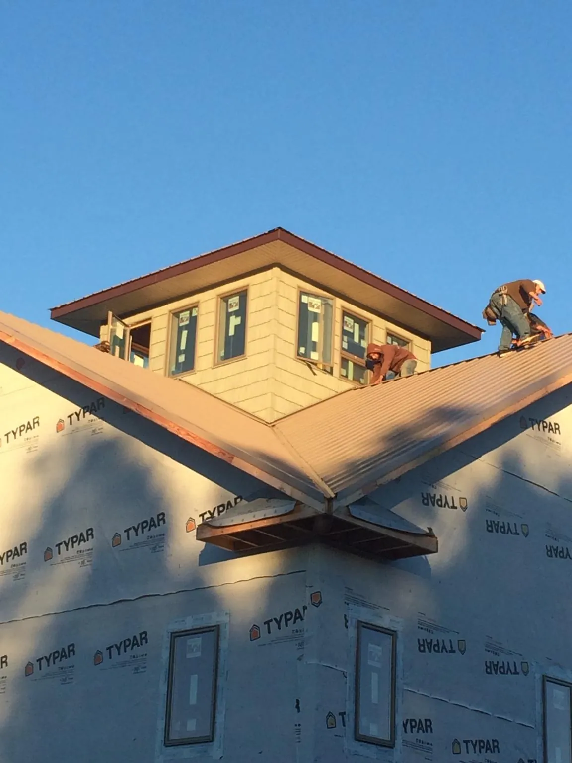 Roofers working around a rooftop cupola on a new metal roof at sunset — Roof Waterproofing in Sumpter by Roofing Brothers